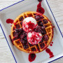 Waffles served with berry compote and vanilla ice cream.